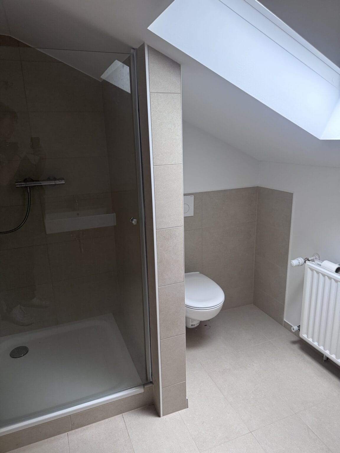 Fertig gefliestes Bad mit Dusche und wandhängendem WC