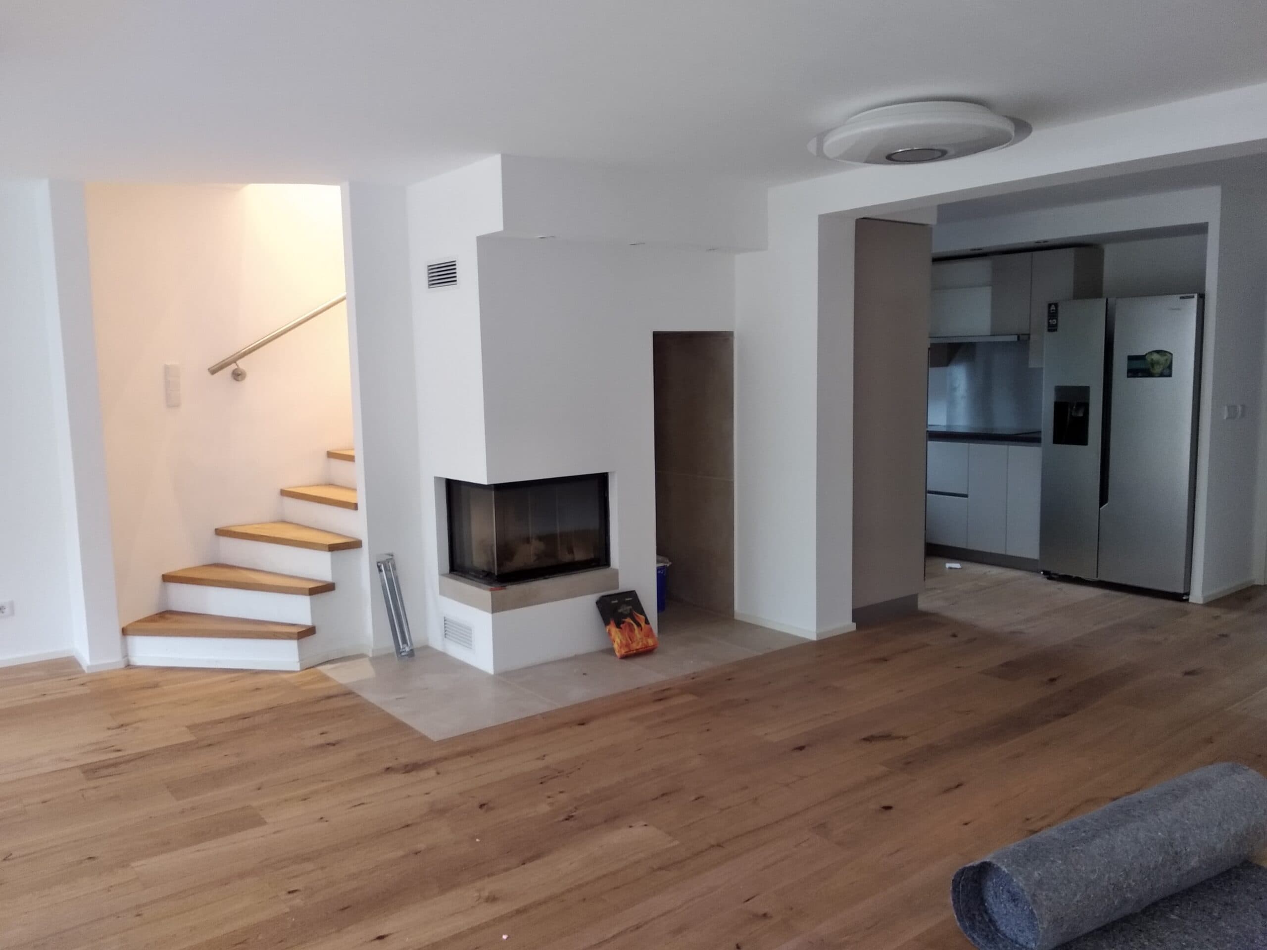 Wohnraum mit Eichendielen, Kamin und offener Treppe nach der Sanierung