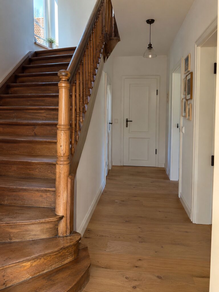 Sanierter Flur mit Eichenboden und erhaltener alter Holztreppe