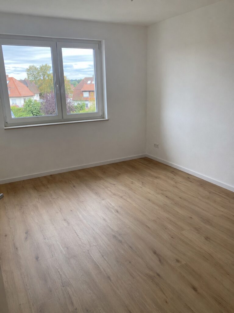 Zimmer nach dem Wiederaufbau: frisch gestrichene Wand und neuer Boden