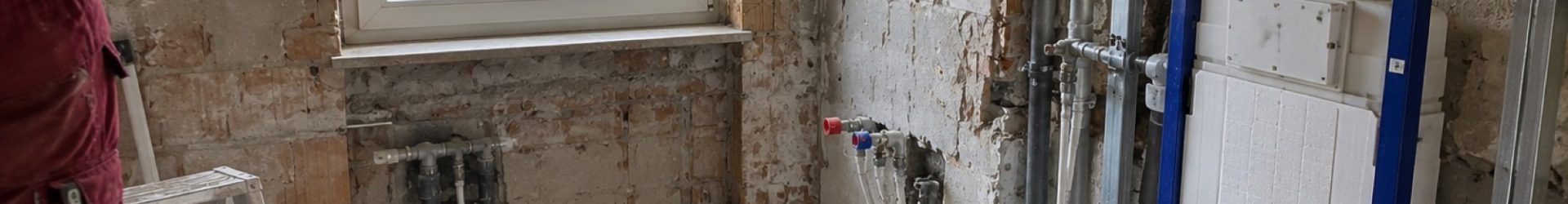 Badsanierung Ablauf: Bad nach dem Rückbau mit neuen Leitungen und Vorwandelement