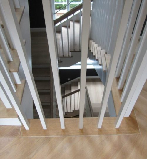 Parkett Grünwald - MR Umbau Eichenparkett und Holztreppe, Blick durch ein weißes Geländer