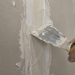 Fuge zwischen zwei Gipsplatten wird mit dem Spachtel glatt gezogen