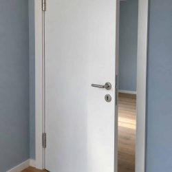 Weiße Zimmertür mit Zarge und Edelstahl-Drücker in einer Münchner Wohnung
